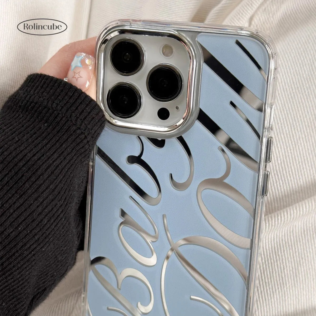 Transparent blue iPhone case with mirror surface and white JMKJ letters showing front and back views