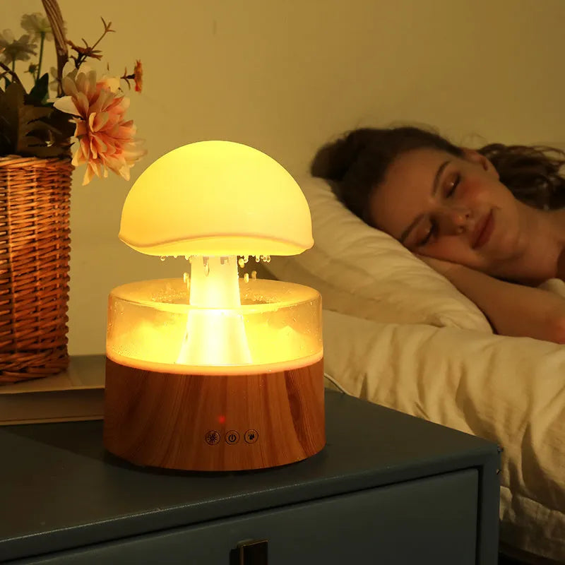 White cloud-shaped humidifier with simulated raindrops and colour-changing lights on wooden surface