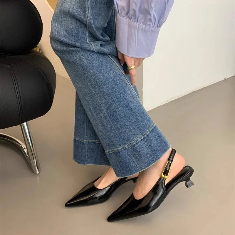 Black pointed toe low heel women's shoes with an ankle strap and rubber sole.