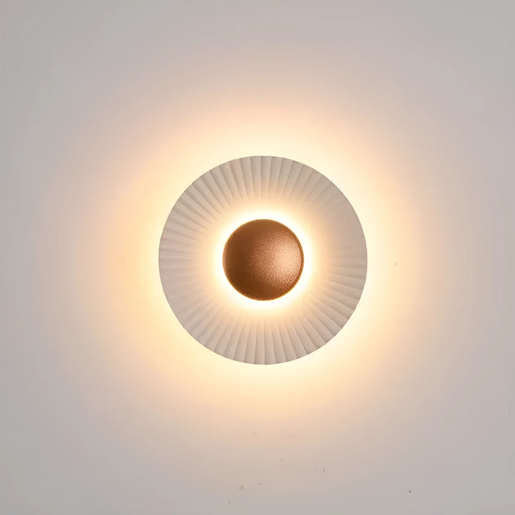 A round, modern wall lamp with an aluminium shade, shown in a two-tone gold and white finish, mounted on a wall.