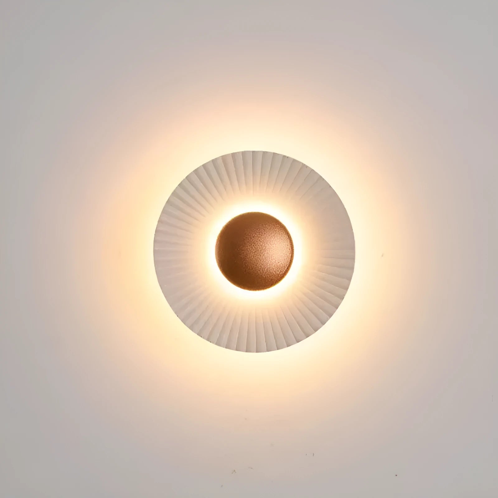 A round, modern wall lamp with an aluminium shade, shown in a two-tone gold and white finish, mounted on a wall.