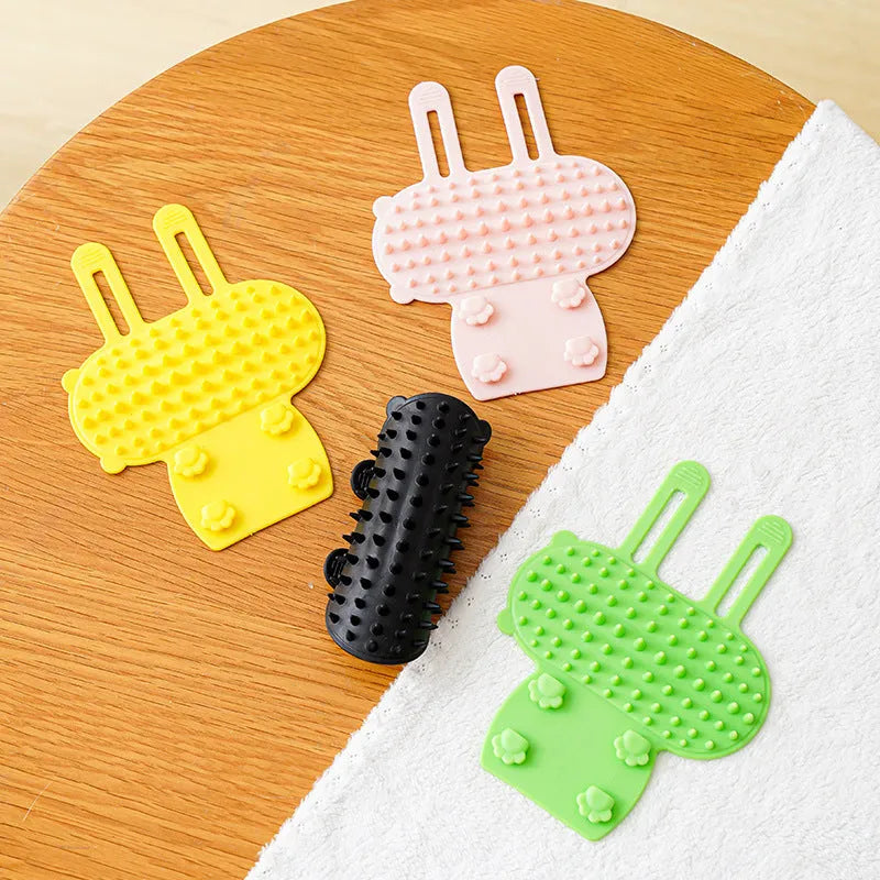 Silicone cat grooming comb with adjustable strap mounted on a table leg.