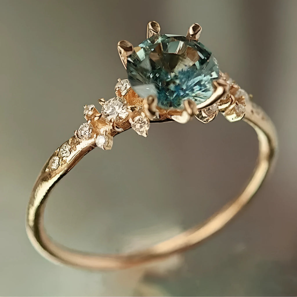 Gold geometric ring with a claw-set zircon stone and a textured square pattern band.