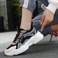 White women's casual mesh sports shoes with a thick sole, buckle detail, and round toe on a plain background.
