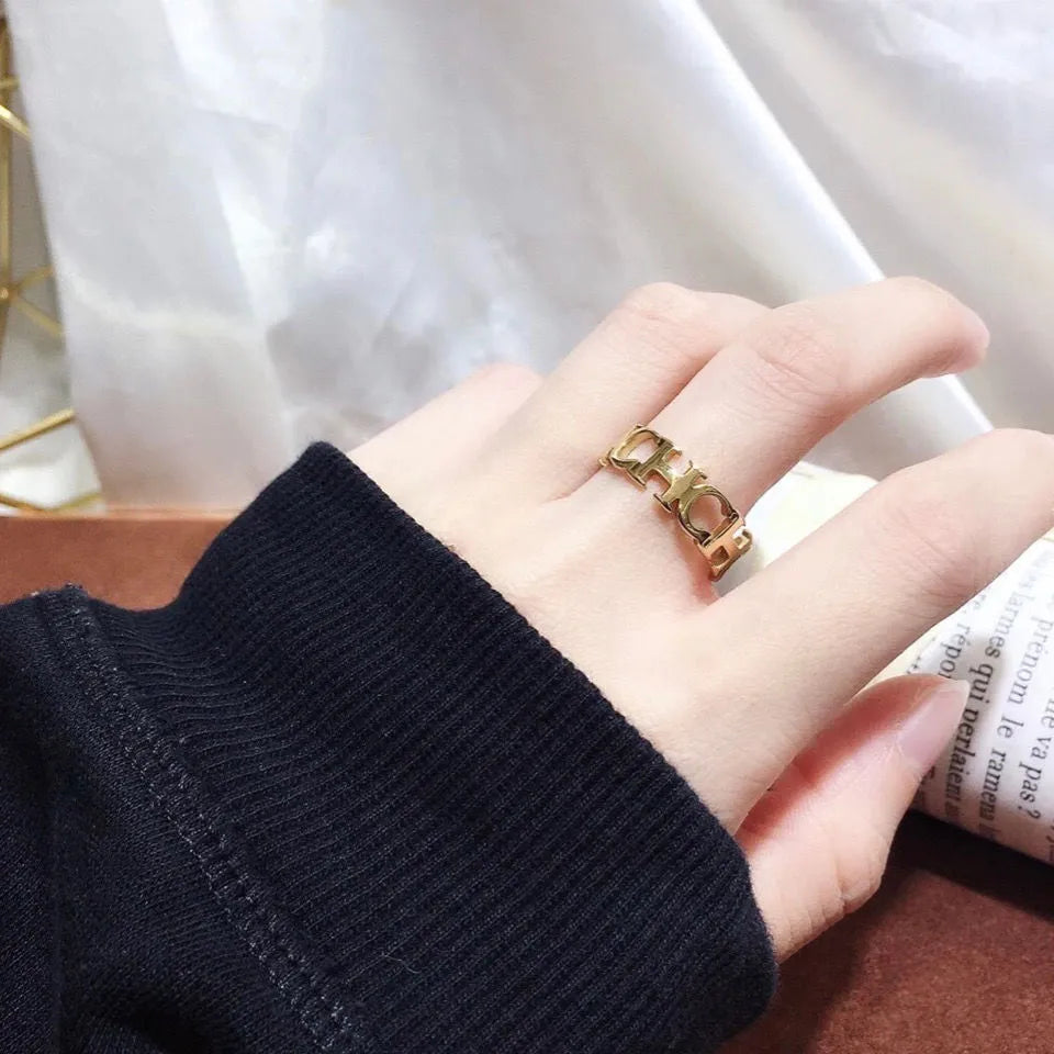 Gold titanium steel hollowed cut letter ring with geometric design on white background