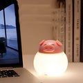 Pink pig silicone pat bedside lamp with USB LED light source on a table