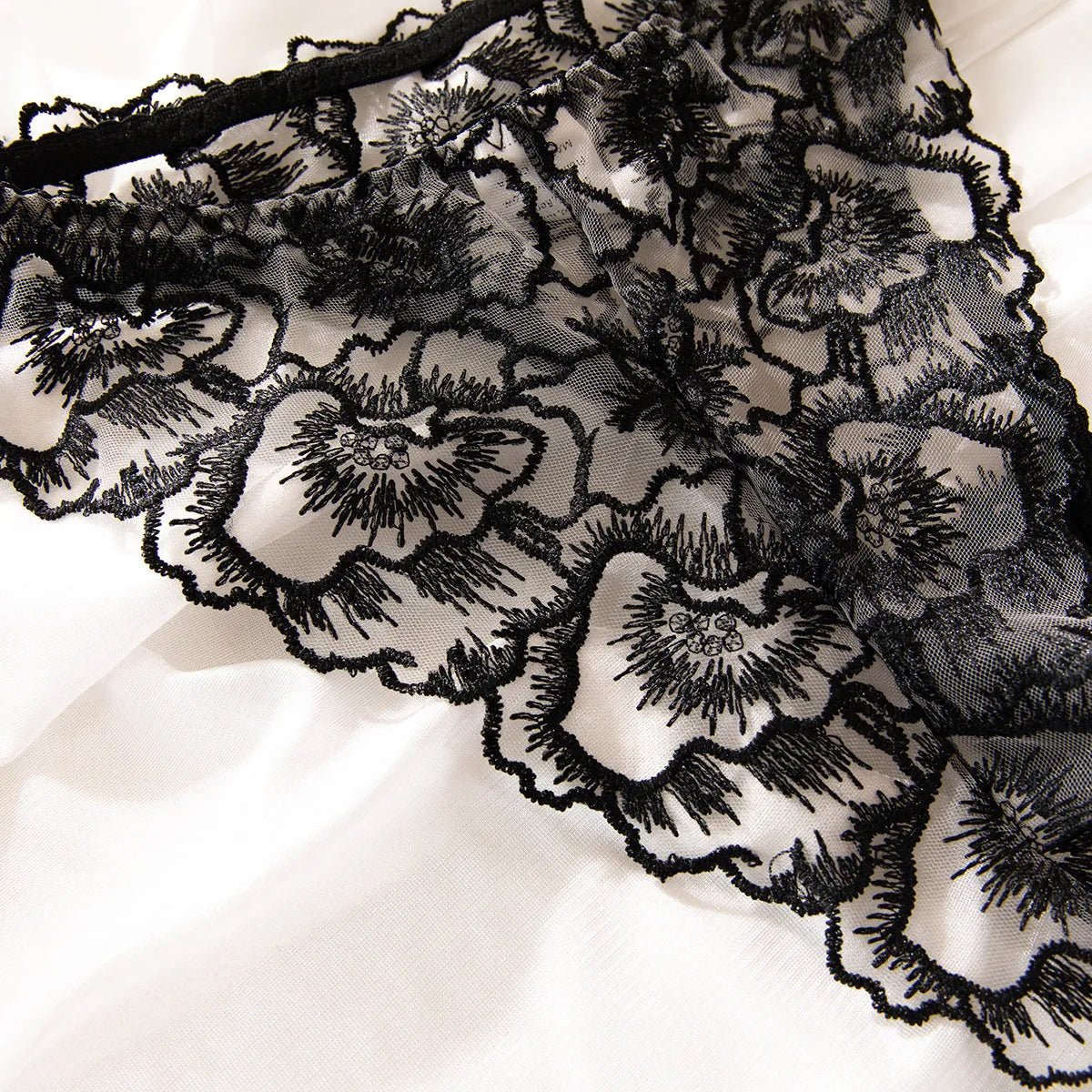 Women's black lace underwear with floral embroidery and steel ring detail on transparent polyester fabric