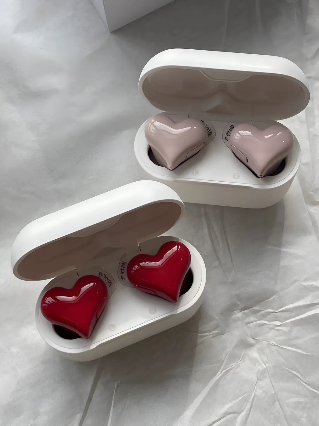 Heart-shaped wireless Bluetooth headphones in red or pink colours with earplug design