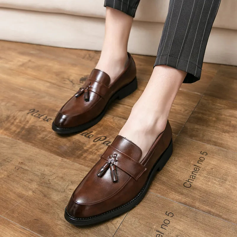 Men's black slip-on business casual shoe with tassel detail and rubber sole.