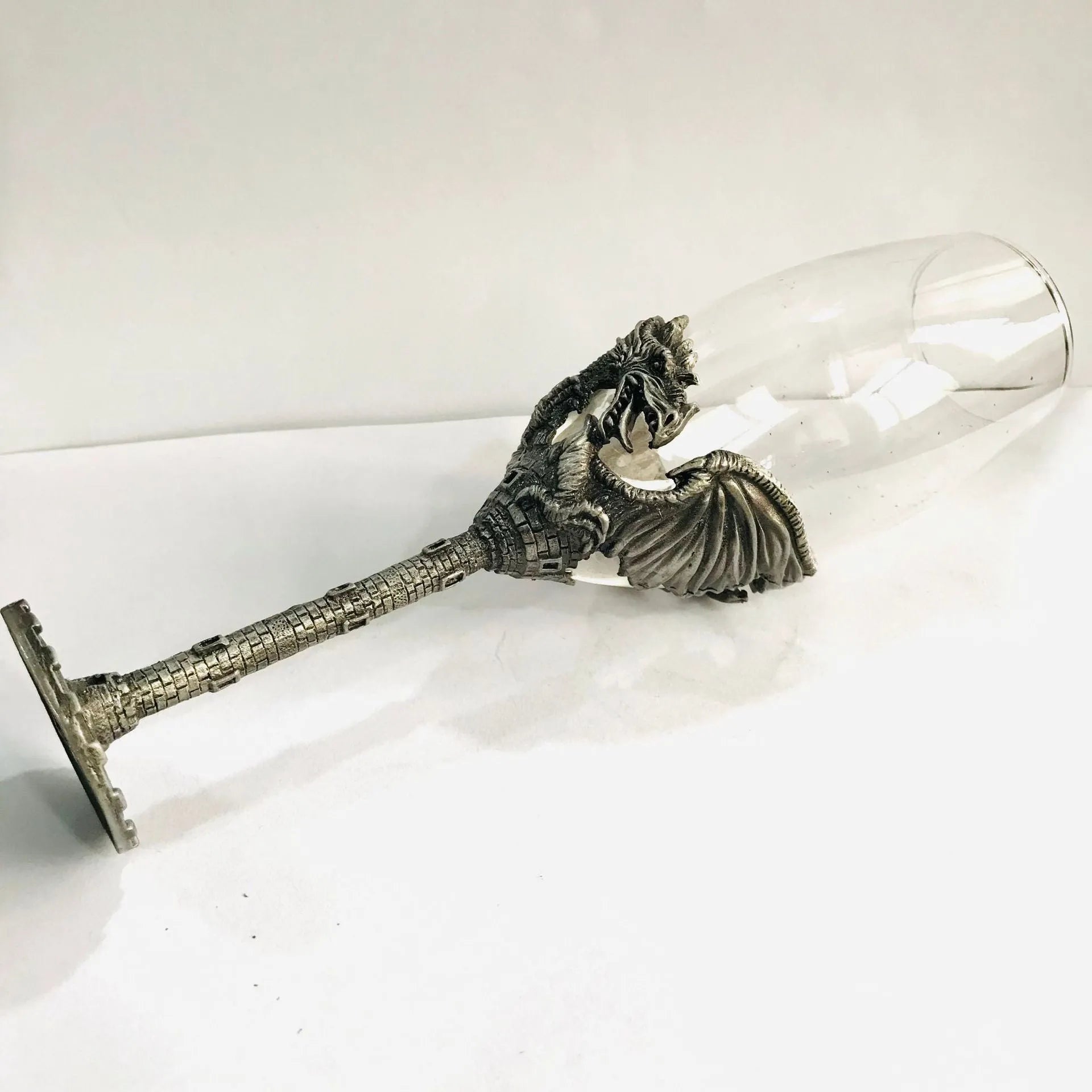 Alloy dinosaur champagne glass goblet in ancient tin colour on a surface, 21cm tall, retro style