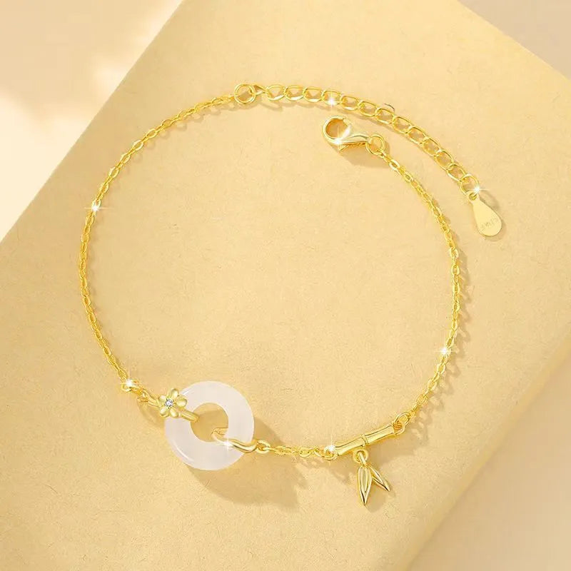 Gold tone women's bracelet with white chalcedony stone and adjustable peace symbol buckle closure