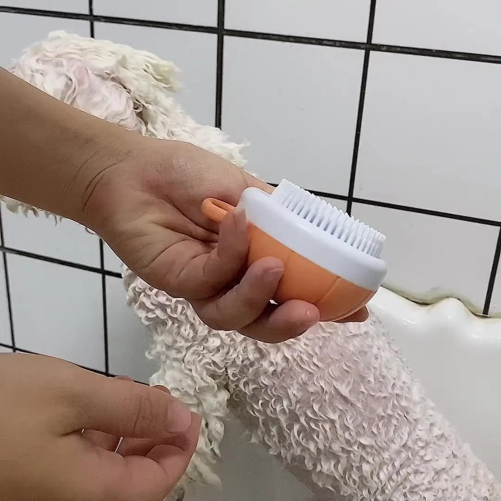 Orange dog bath brush with shampoo dispenser and soft TPR bristles on a curved pumpkin-shaped handle.