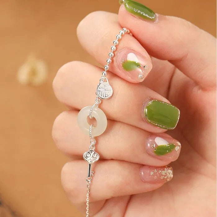 Women's silver bracelet with a geometric Hetian jade peace buckle charm on a chain.
