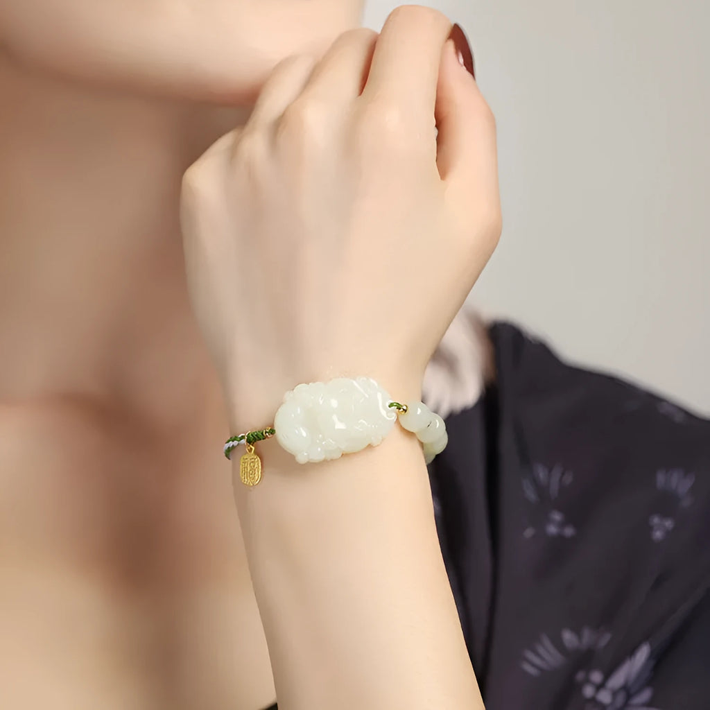 Hetian jade Rabbit charm bracelet on a red rope with a small silver blessing card.