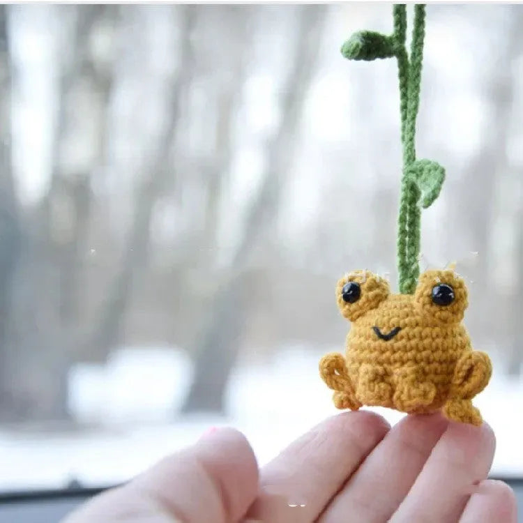 Handmade woven plush frog car pendant in green hanging from rear-view mirror
