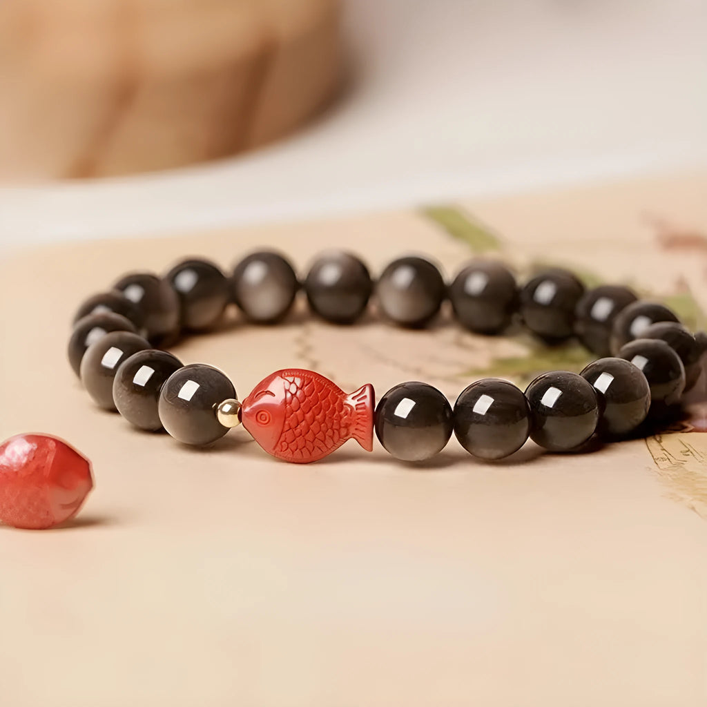 Natural obsidian bracelet with round beads and red cinnabar fungus decoration on wrist