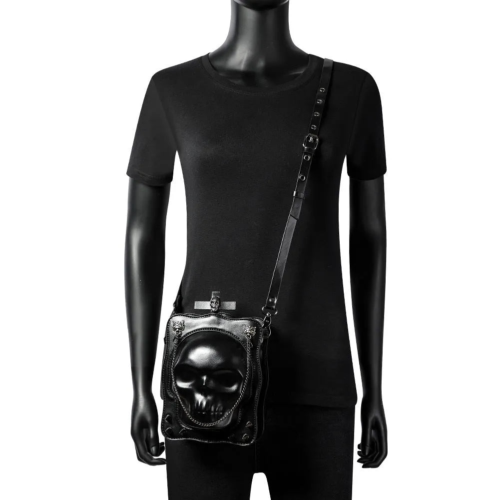 Black mini square crossbody bag with embossed skull design and metal chain strap