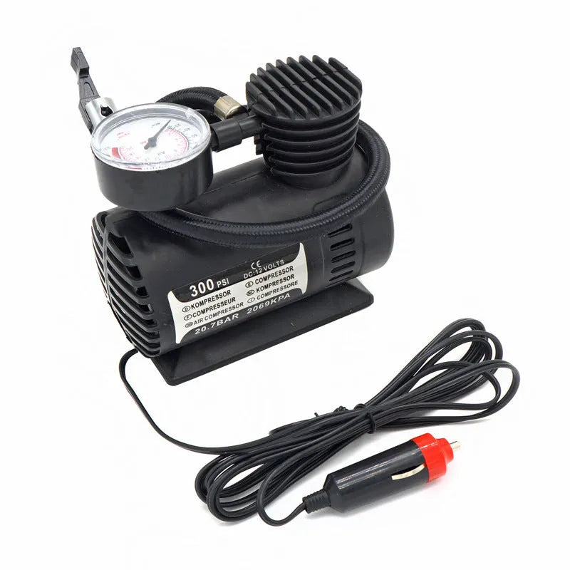 Black portable 12V mini car air compressor with pressure gauge, hose, and two nozzle adapters on grey background