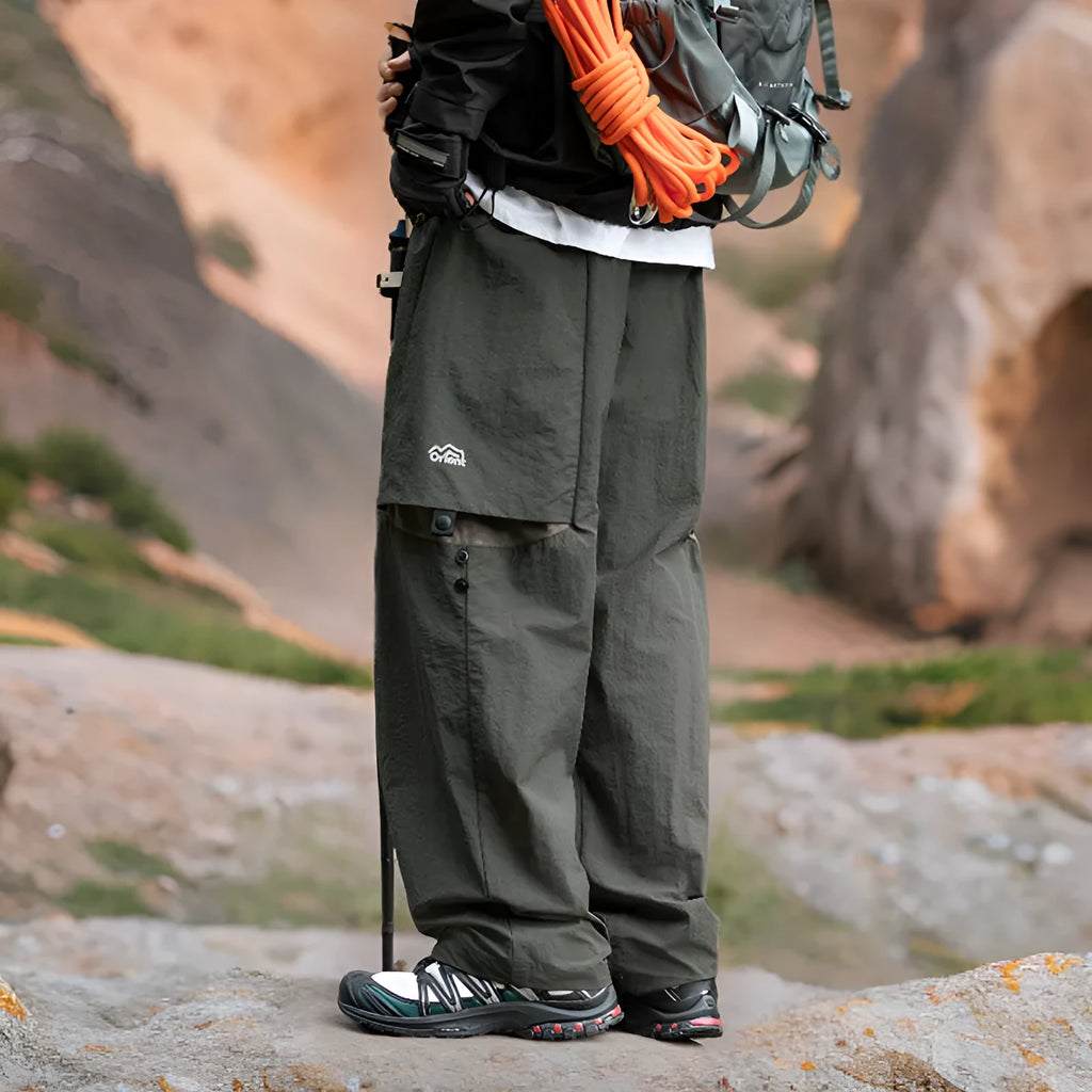 Men's loose-fit nylon casual trousers in black, grey green, or greige, with adjustable split and breathable fabric.