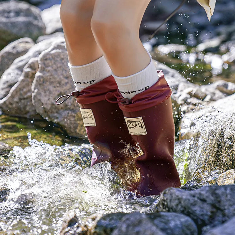 A pair of high tube PVC rain boots in a solid colour, shown on a non-slip sole.