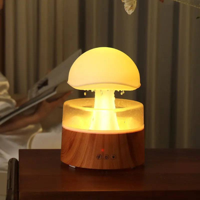 White cloud-shaped humidifier with simulated raindrops and colour-changing lights on wooden surface