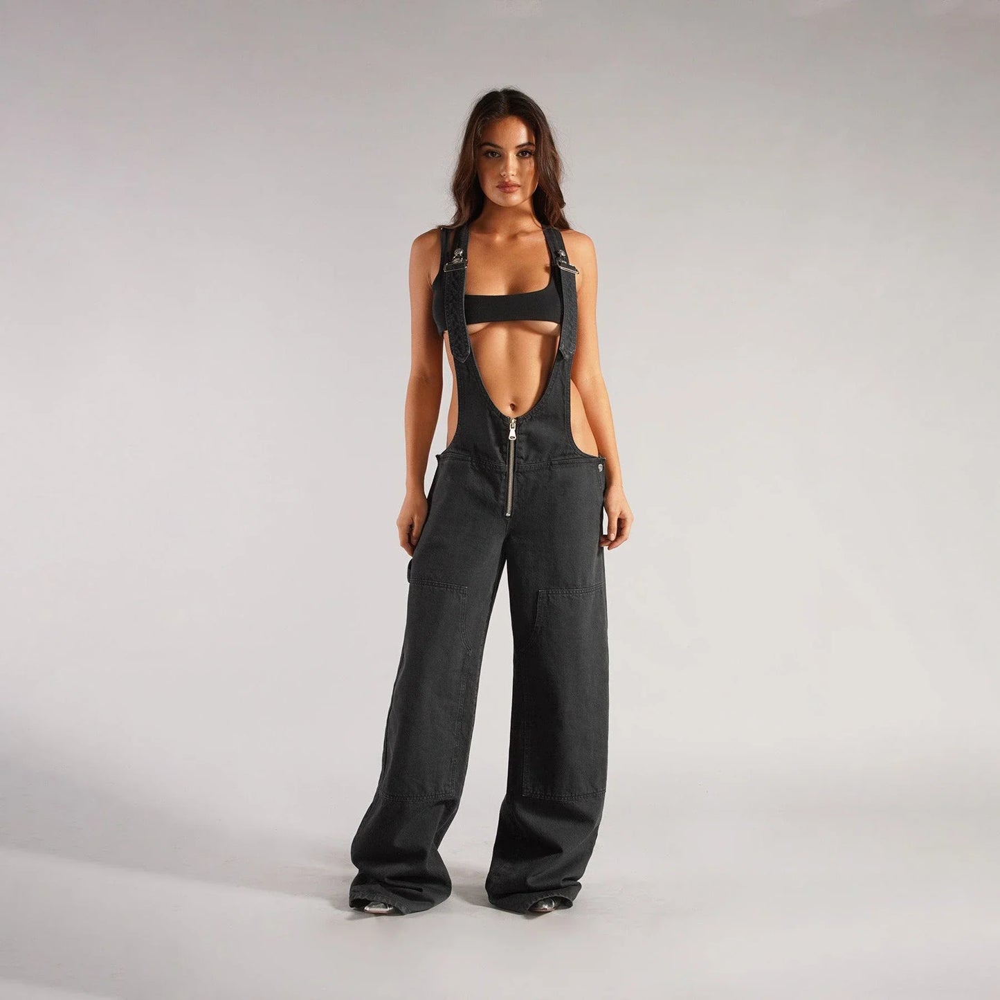 Stylish Y2K-inspired denim suspender jumpsuit with pockets, featuring a relaxed wide-leg silhouette and adjustable straps for a customized fit.