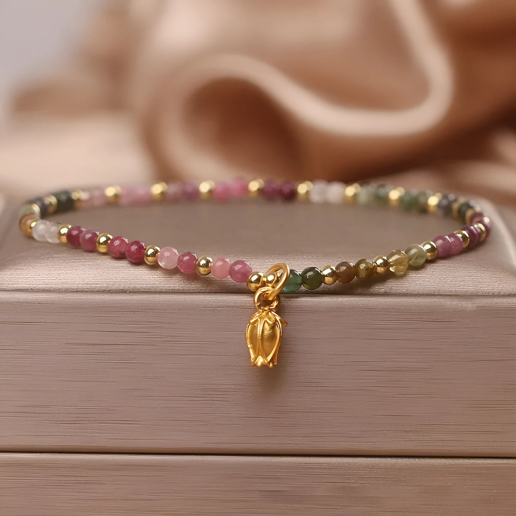 Natural tourmaline beaded anklet with a floral charm, shown being worn.