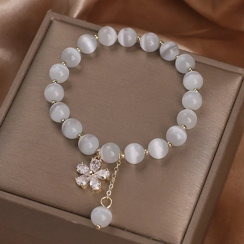 White cat's eye stone single-loop bracelet with a safety buckle, pendant, and small flower tassel decoration.