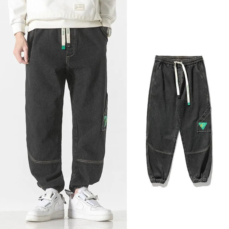 Man wearing loose-fit tapered trousers in grey, showing the mid-waist and tapered leg design.