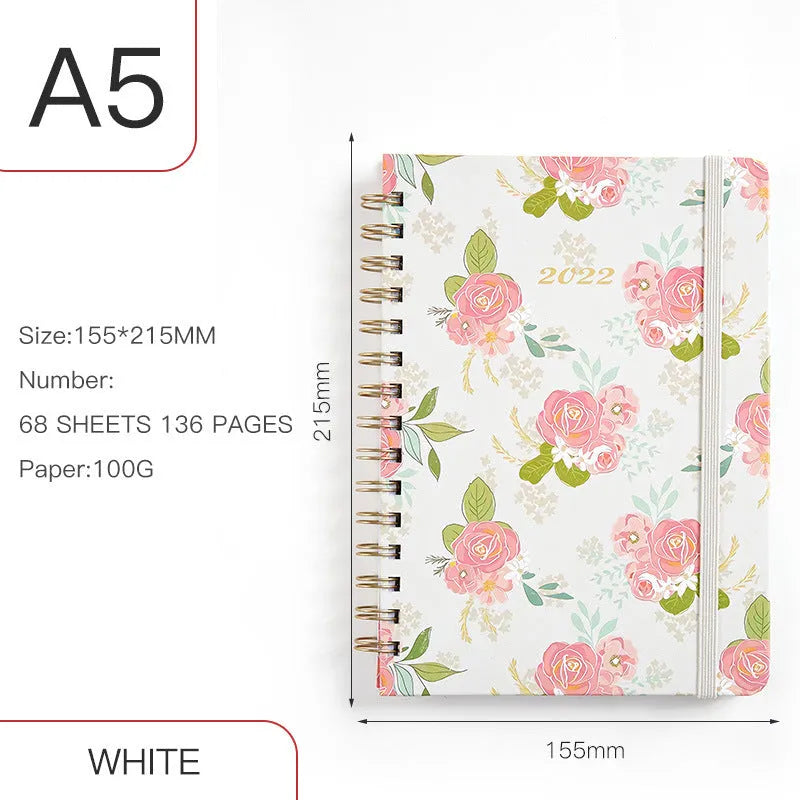 A5 spiral-bound notebook with a colourful floral design cover, lying open on a table.