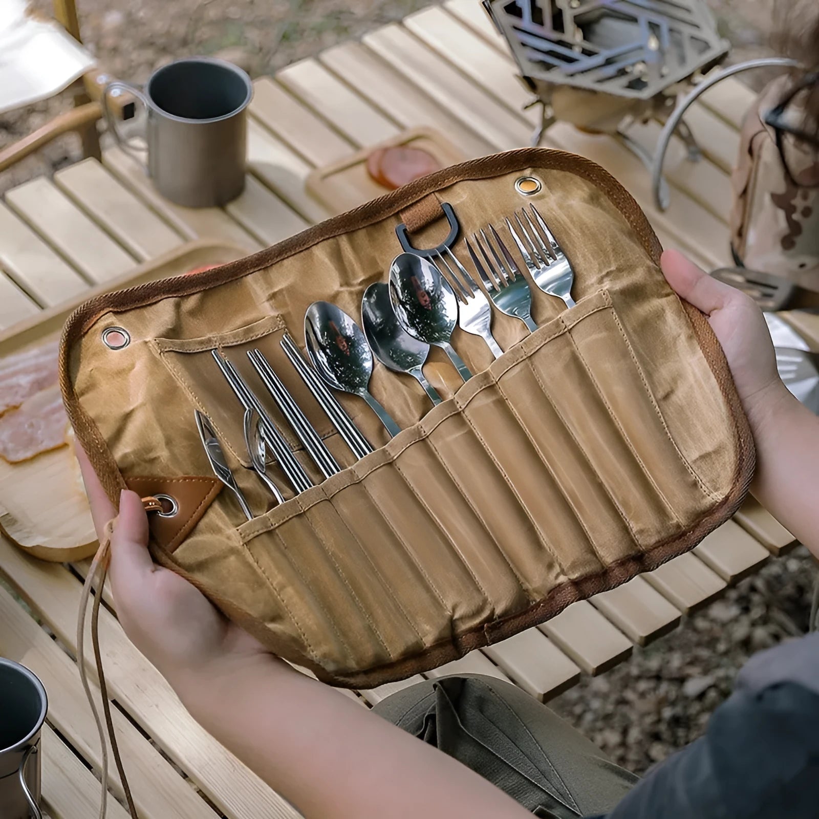 Waxed canvas portable storage bag containing a wooden handle knife, fork, spoon, butter knife, and chopsticks for outdoor dining.