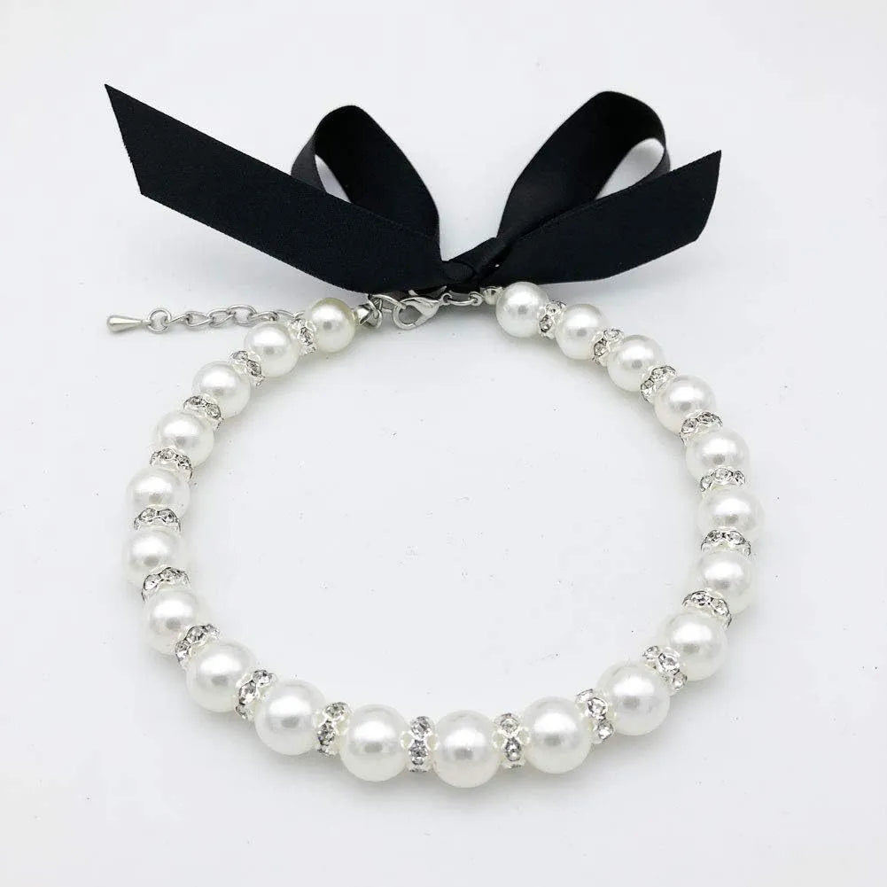 Small dog wearing adjustable pearl and rhinestone necklace with soft ribbon bow in pink colour