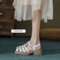 Women's black retro platform sandals with closed toe, hollow out holes, and a silver buckle closure on a chunky rubber heel.