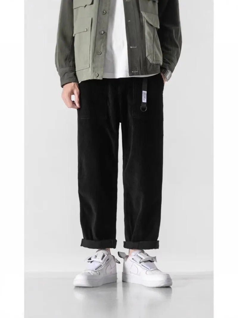 Man wearing loose straight leg tapered trousers in dark grey, showing relaxed fit and straight leg opening.
