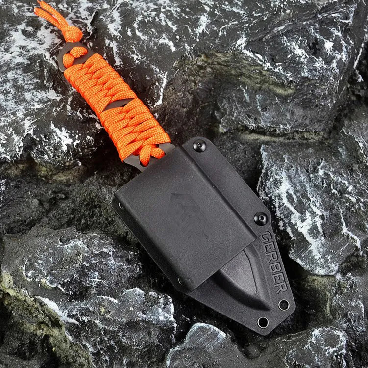 Straight blade outdoor survival knife with binding rope handle next to ABS plastic sheath