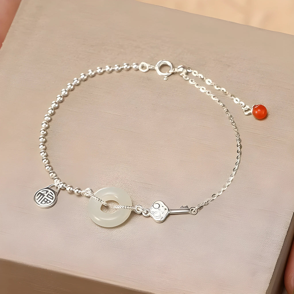 Women's silver bracelet with a geometric Hetian jade peace buckle charm on a chain.