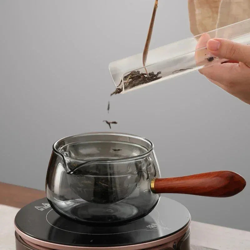 Transparent borosilicate glass teapot with wooden handle and infuser on rotary base