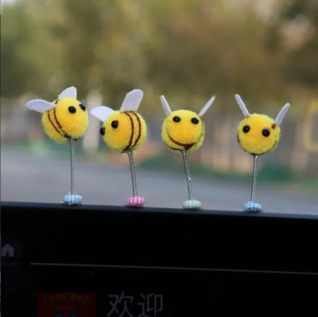 Small black and yellow cartoon bee car decoration with a spring, on a fur ball.