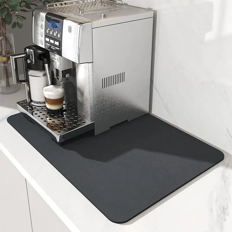 Black square rubber-backed kitchen drying mat on a countertop next to a coffee cup