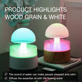 White cloud-shaped humidifier with simulated raindrops and colour-changing lights on wooden surface