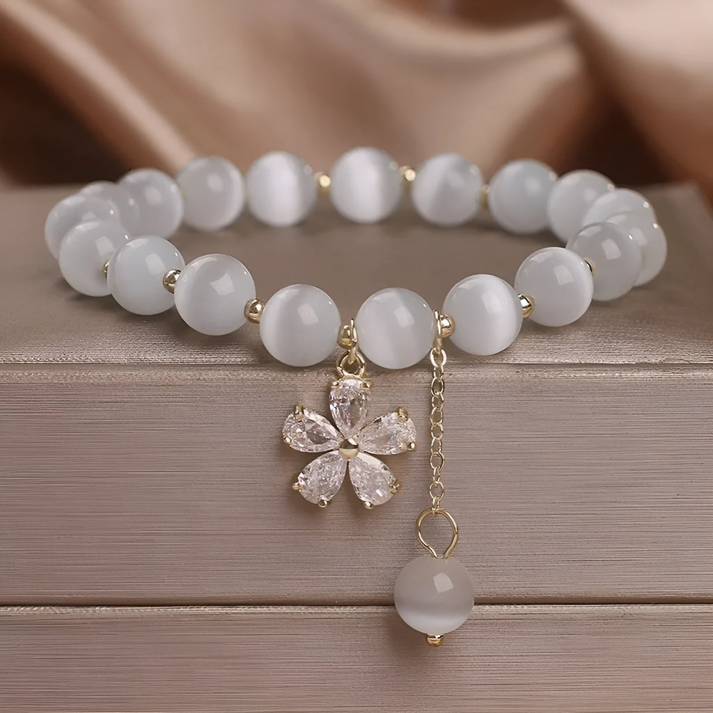 White cat's eye stone single-loop bracelet with a safety buckle, pendant, and small flower tassel decoration.