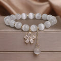White cat's eye stone single-loop bracelet with a safety buckle, pendant, and small flower tassel decoration.