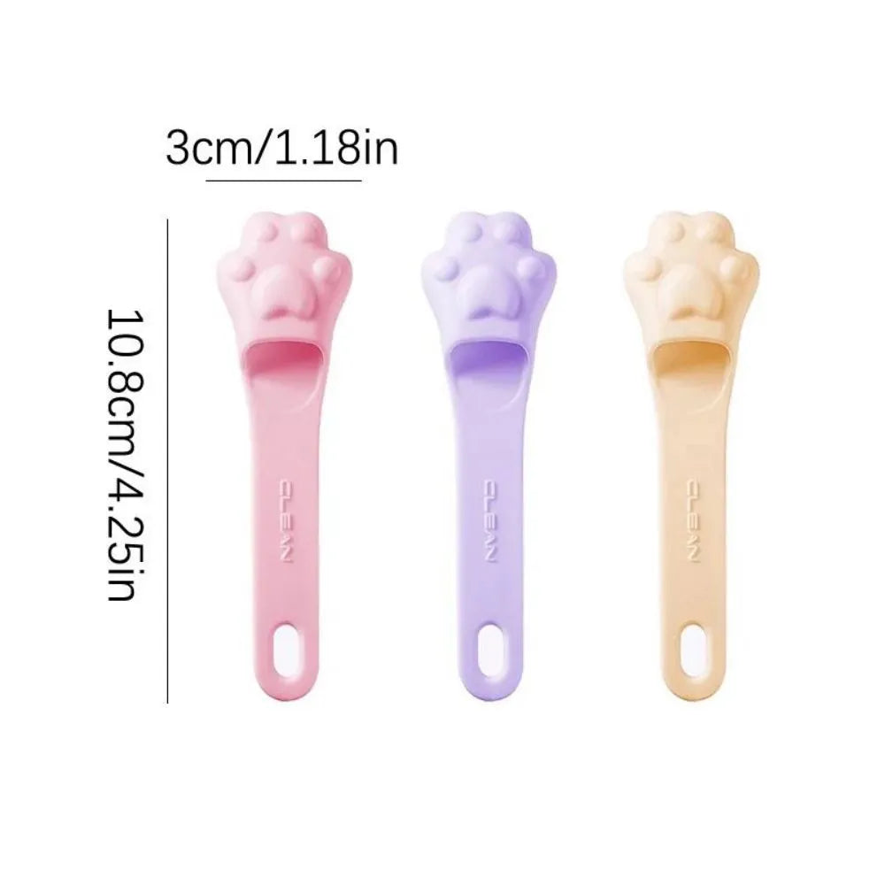 Silicone fingertip toothbrush for pets in pink, purple, and yellow, shown on a finger.