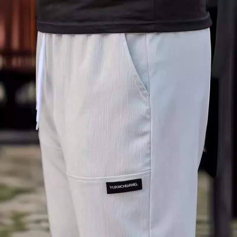Men's light grey casual chino-style trousers made from polyester for spring and autumn wear.