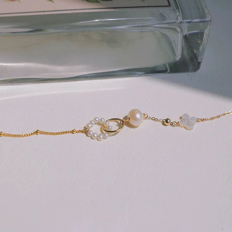 Women's natural pearl and gold-plated chain bracelet on a white background.