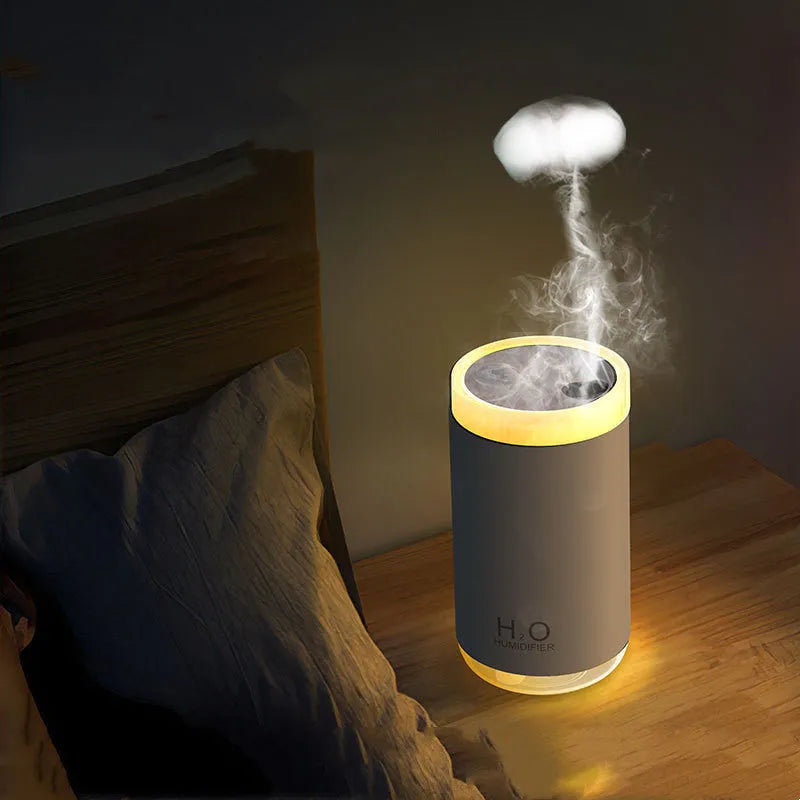White USB humidifier emitting jellyfish-shaped smoke ring mist with warm night light glow on a table