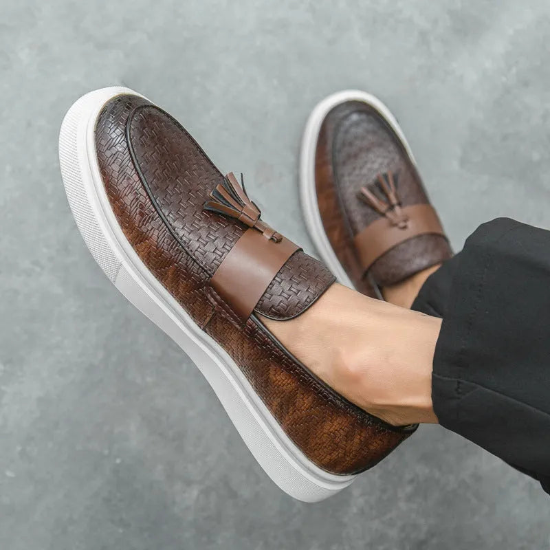 Men's black casual leather shoes with fringe detail on round toe, showing low heel profile.