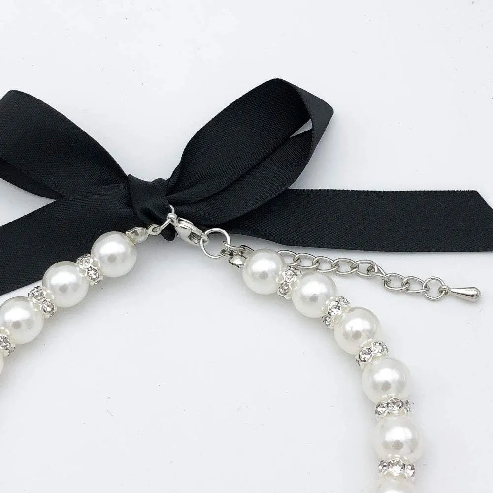 Small dog wearing adjustable pearl and rhinestone necklace with soft ribbon bow in pink colour