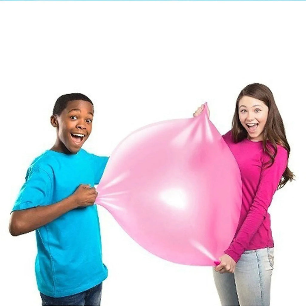 Large pink, yellow, green, and blue inflatable bouncy balls in different sizes for outdoor play.