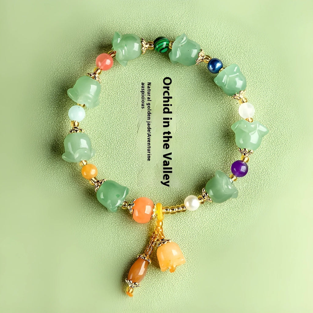 Close-up of a women's jade bracelet with hand-carved orchid-shaped beads on a wrist.